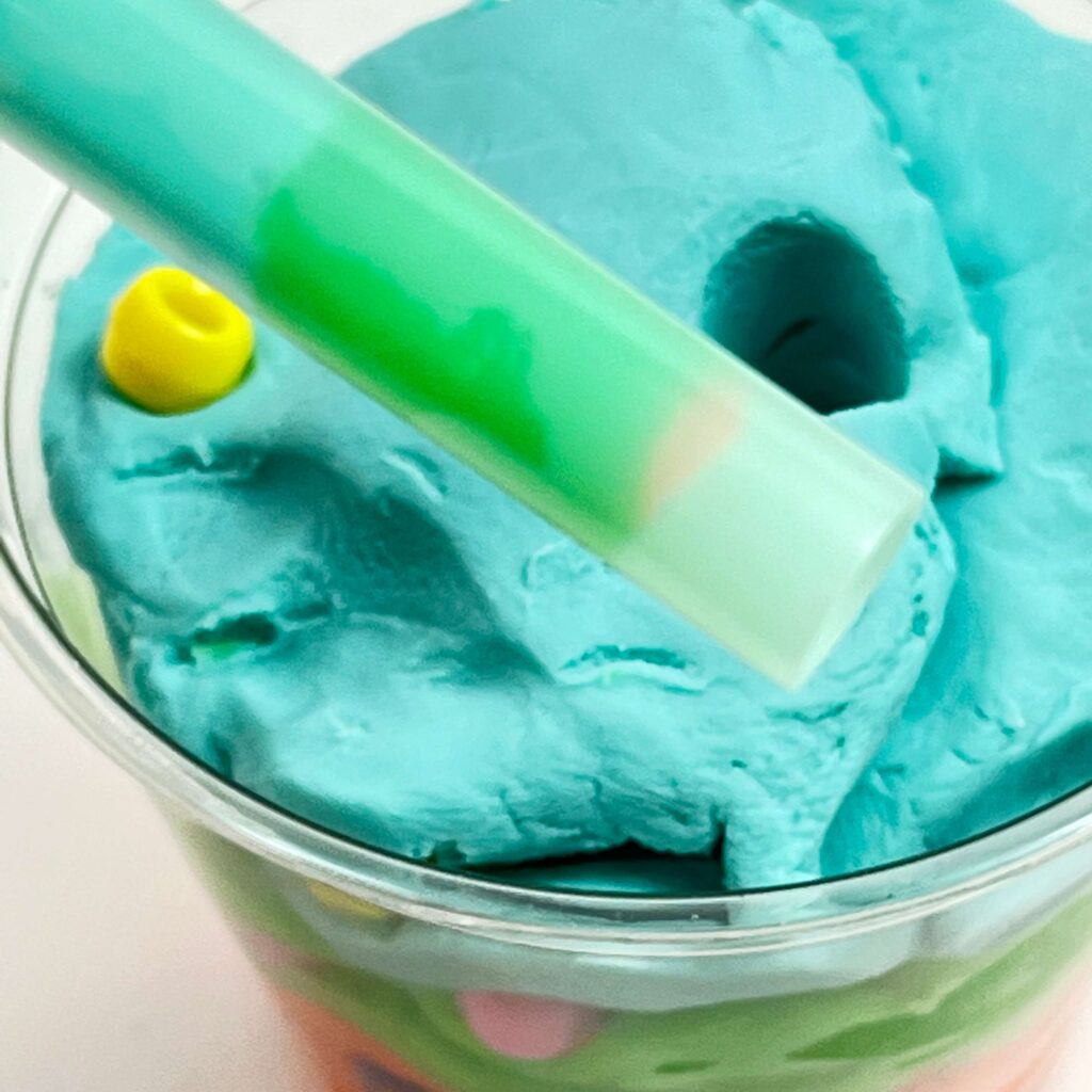 Taking a core sample of the Play-Doh layers in a geologic time scale model using a straw.